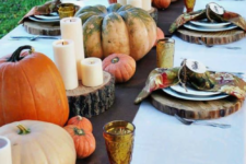 a bright fall table with a brown runner, wood slice placemats, natural pumpkins and pillar candles