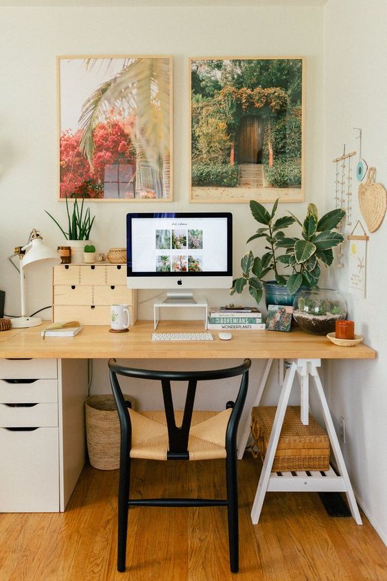 A chic mid century modern boho home office with a desk, a chic chair, a tropical gallery wall and potted plants