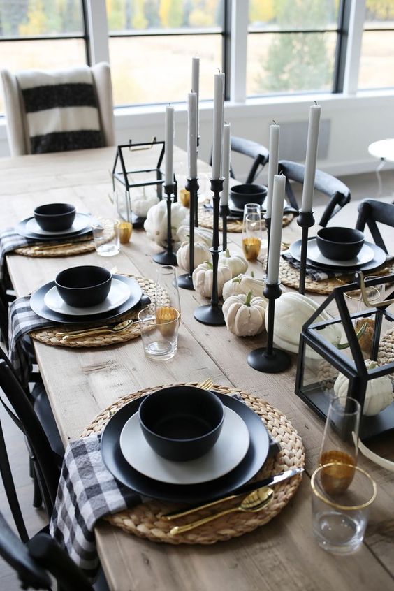 a chic modern farmhouse tablescape with plaid napkins, blakc tableware and candleholders, white pumpkins and candles