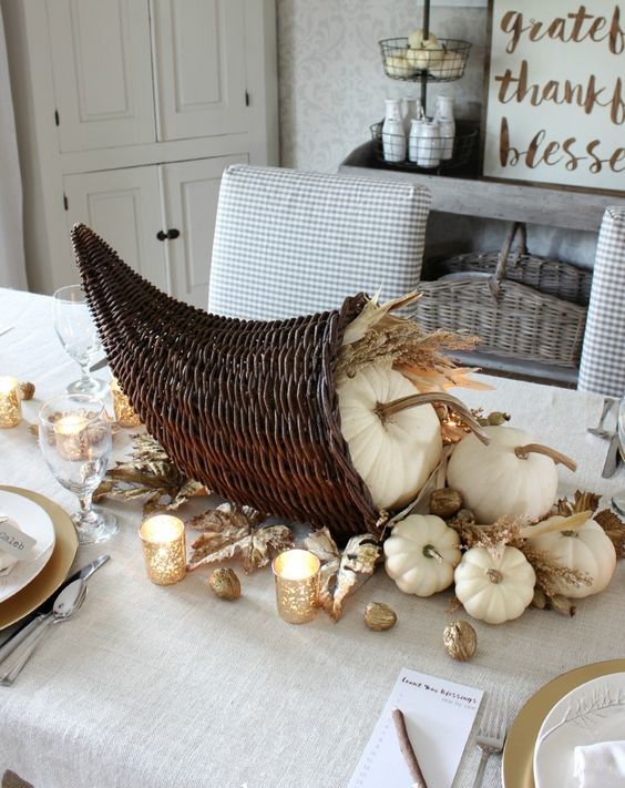 a cornucopia with white pumpkins, wheat, gilded leaves and nuts and candles is a lovely fall centerpiece