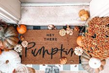 a cozy fall porch with lots of pumpkins, gourds and leaves, bright fall blooms and layered mats