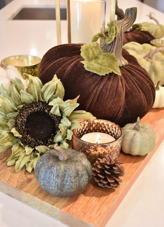 a cutting board with fake pumpkins, blooms, candles and pinecones for durable rustic decor