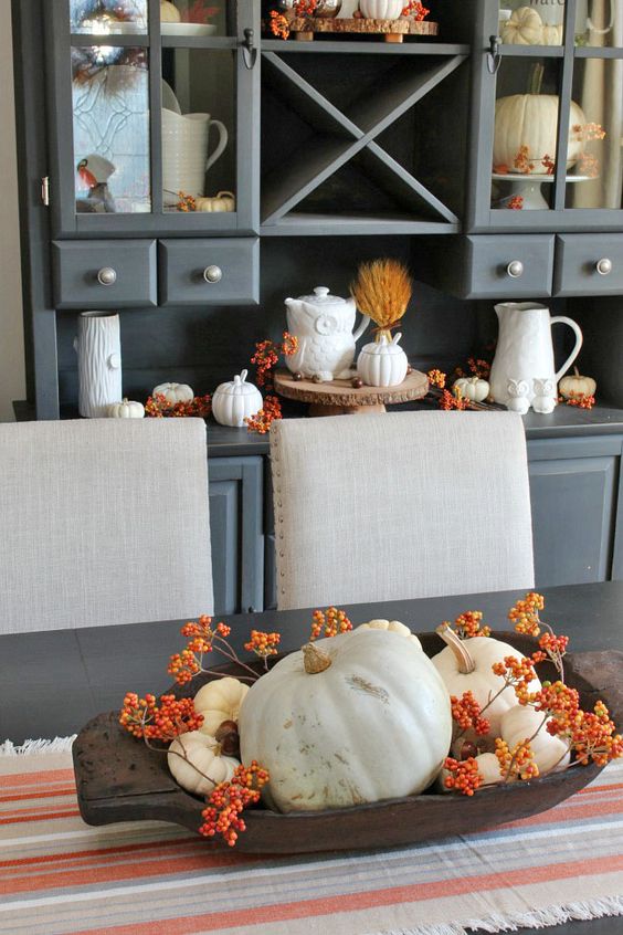 a dough bowl with berries and white pumpkins, and similar decor on the buffet behind