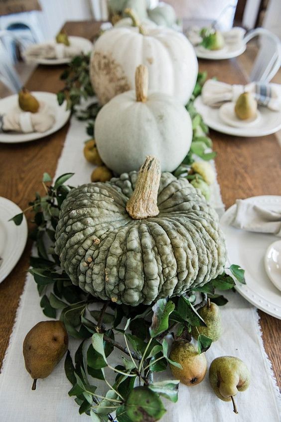 a farmhouse fall centerpiece of various pumpkins, foliage and pears is harvest-loving and very fall-like piece