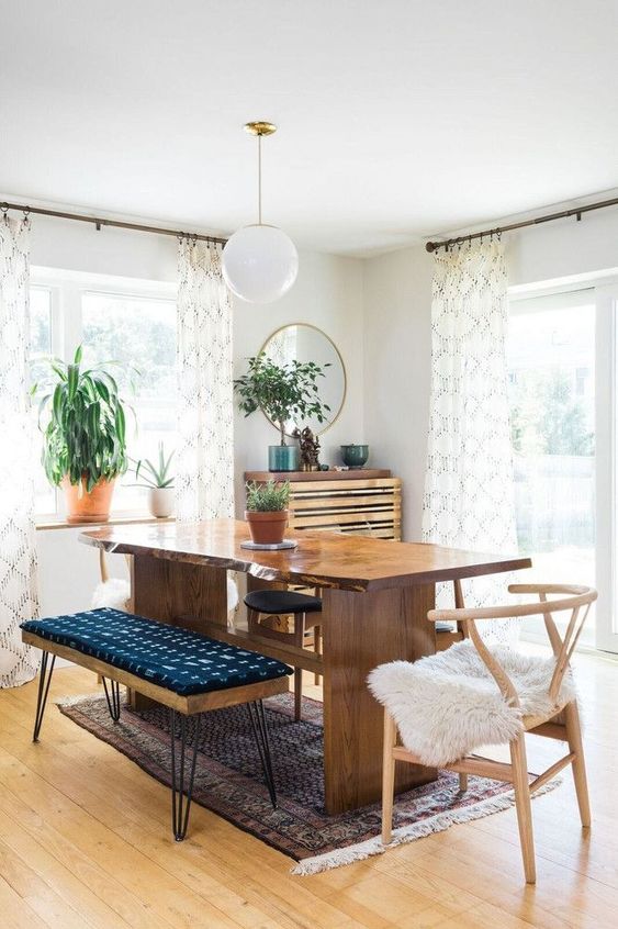 a mid-century modern meets boho dining space with a live edge table, a hairpin ottoman, potted greenery