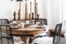 a modern meets boho dining space with a bead chandelier, rattan and wooden furniture, wooden candleholders