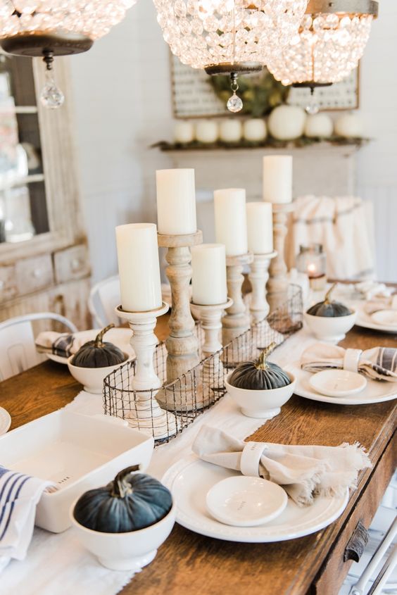 a neutral farmhouse chic tablescape with dark fabric pumpkins, wooden candleholders and striped napkins