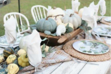 a neutral farmhouse table with woven palcemats, printed plates, natural veggies and pumpkins plus greenery
