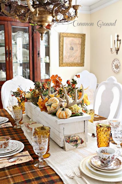 a rustic fall centerpiece of a white box with faux pumpkins, antlers, bold leaves and vine is vintage and elegant