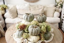 a rustic fall decoration of stacked heirloom pumpkins and green hydrangeas is a lovely centerpiece or just decoration
