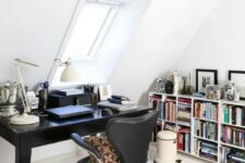 a stylish Scandinavian home office with wooden beams, a vintage black desk, a black leather chair, a large bookshelf, some rugs and pillows