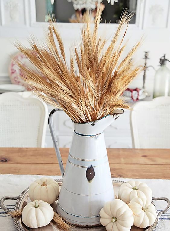 a stylish farmhouse fall centerpiece with a metal jug with wheat and white pumpkins on a silver tray