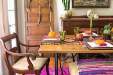 a super colorful boho dining room with a dream catcher, elegant wooden furniture, potted cacti and colorful textiles