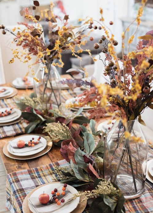 a super natural fall tablescape with plaid placemats, berries, fruits, foliage and dried herbs and blooms in vases