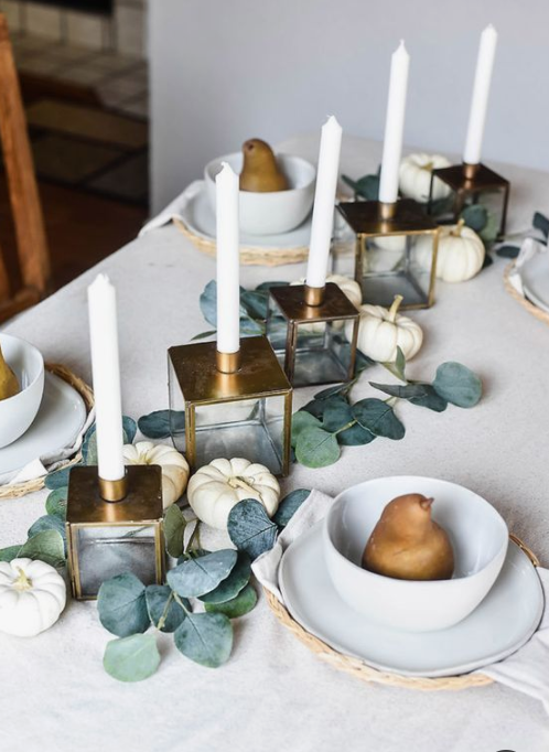 a very siple yet elegant fall tablescape with greenery, white pumpkins, candles in gold candleholders and pears for each palce setting
