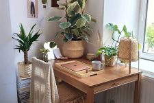 a welcoming boho nook with a desk, a wooden chair, potted plants, lights, a rattan lamp and baskets is very cozy and warming