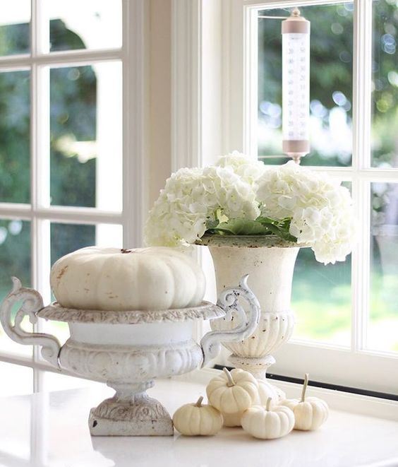 a white fall decoration of vintage urns, white pumpkins and blooms is very elegant and chic