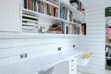 a white shared home office with open shelves over the shared desk, white Eames rockers and a file cabinet under the desk