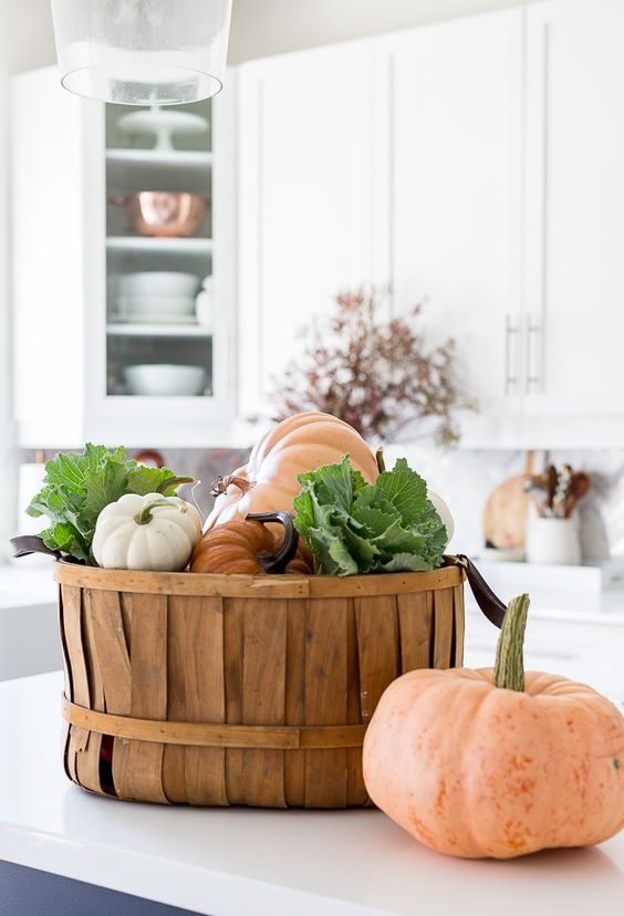 a wooden basket with fresh pumpkins and veggies is a cool and edible fall decoration