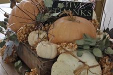 a wooden crate with dried hydrangeas, greenery, pumpkins, a black sign and los of twigs for a rough fall centerpiece