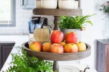 a wooden stand with potted greenery, fresh apples and pears plus pumpkins and plates