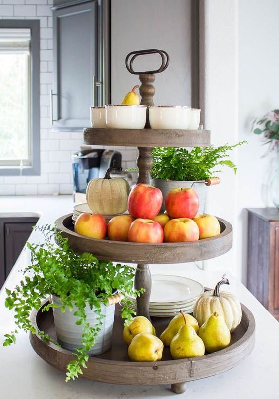 a wooden stand with potted greenery, fresh apples and pears plus pumpkins and plates