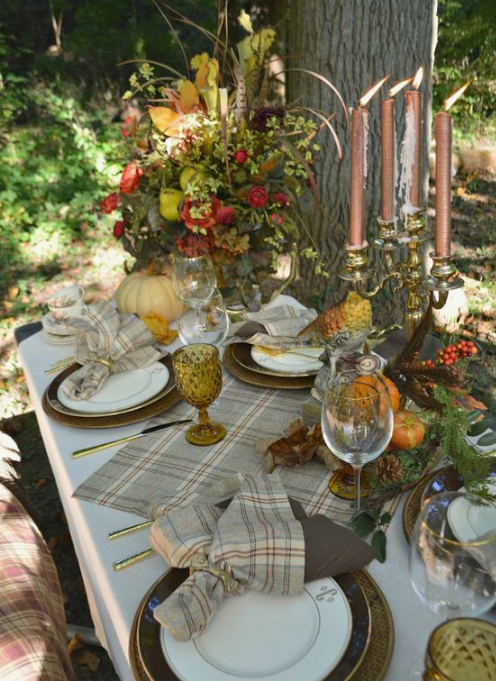 a woodland fall tablescape with plaid textiles, fall blooms and foliage, copper candles and printed plates