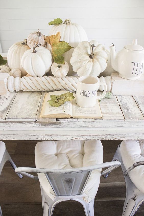 an airy fall centerpiece of white and neutral pumpkins, fall leaves and railing for a neutral vintage look
