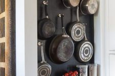 an open storage unit with open shelves and a chalkboard with hooks attached, which are ideal for hanging pots and pans