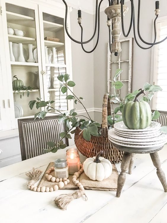 fall kitchen decor with white and green pumpkins, candles, wooden beads and a basket with greenery