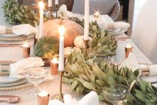 natural pumpkins and a greenery garland plus candles decorate a fall tablescape in a very chic way