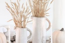 rustic white fall decor with a neutral table runner, white pumpkins, white jugs with wheat and candles