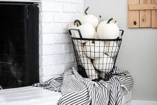 white pumpkins in a black wire basket and a a striped blanket for styling your space for the fall