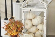 white pumpkins in an oversized white glass candle lanterns, a porcelain pumpkin and candles for fall decor