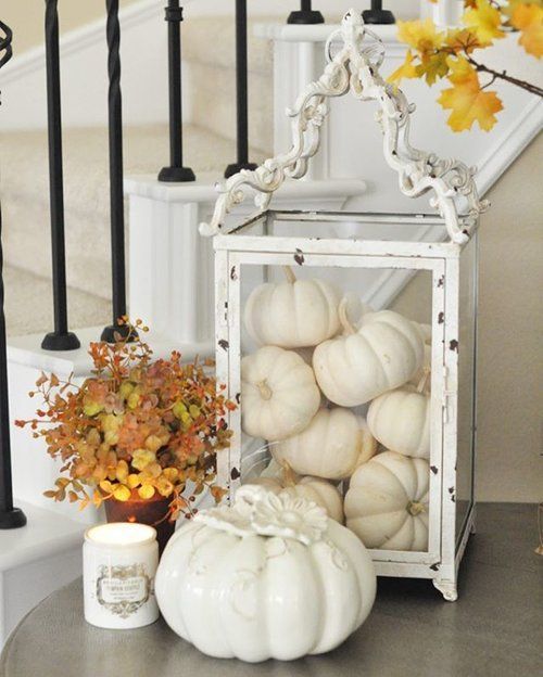 white pumpkins in an oversized white glass candle lanterns, a porcelain pumpkin and candles for fall decor