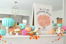 a beautiful colorful mantel with bright garlands, bold pumpkins, faux birds and a cool yarn sign