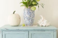 a blue printed vase with blooming branches, a large seashell and a neutral pumpkin for coastal fall decor