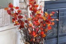 a bold fall decoration of a basket with thick birch branches and branches with bright leaves