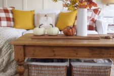a bold fall leaf arrangement in a jug and some natural pumpkins for a rustic fall coffee table