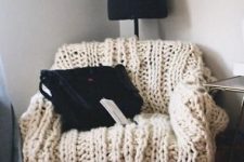 a chair covered with neutral chunky knit is a gorgeous piece to sit on and its imperfect look is very chic