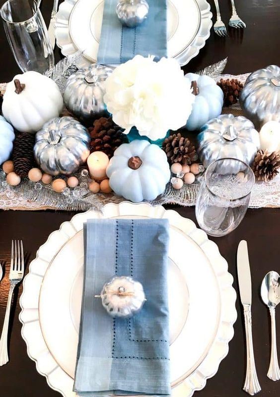 a chic fall tablescape with light blue pumpkins, blue napkins, silver touches, pinecones and wooden beads