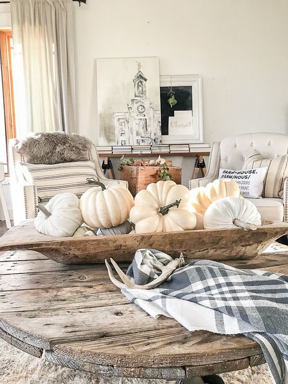 a dough bowl with natural and fabric pumpkins in neutrals, a plaid napkin and antlers