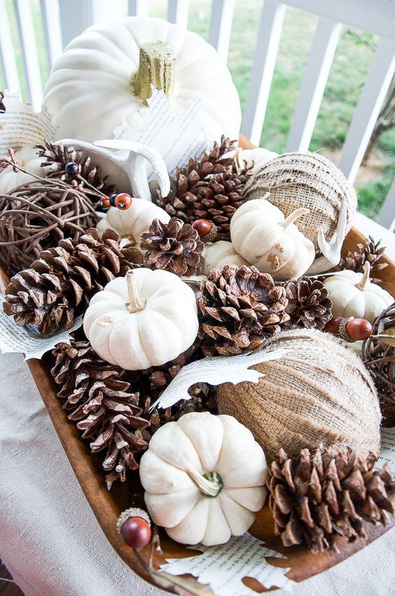 a fall party centerpiece with pinecones, natural white pumpkins, burlap balls and paper leaves