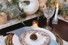 a fall table setting with woven placemats, pinecones, fabric and natural pumpkins and fresh eucalyptus