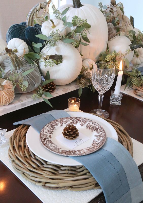 a fall table setting with woven placemats, pinecones, fabric and natural pumpkins and fresh eucalyptus