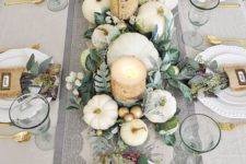 a fall tablescape with white pumpkins, candles wrapped with birch bark, gold cutlery and burlap pockets with blooms and greenery