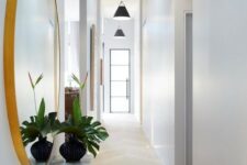 a long white Scandinavian hallway with black pendant lamps hanging in a row feels airy and lit up
