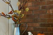 a metal jug with branches and fake fall leaves plus a pumpkin are simple fall decorations to go for