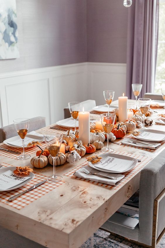 a natural fall table setting with little faux pumpkins, pillar candles and plaid placemats