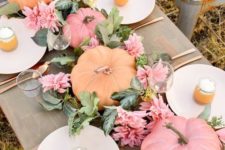 a pastel fall tablescape with pink blooms, greenery, pastel pumpkins and copper cutlery to finish off the look